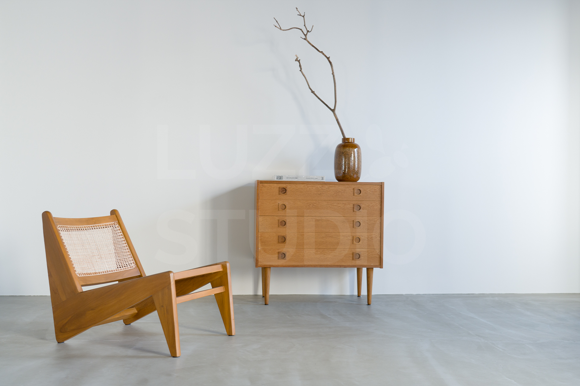 大阪のレンタル撮影スタジオ。北欧ヴィンテージの木製チェストとラウンジチェアを配した、モルタルグレー壁と白壁が美しいナチュラルモダンな撮影スペース