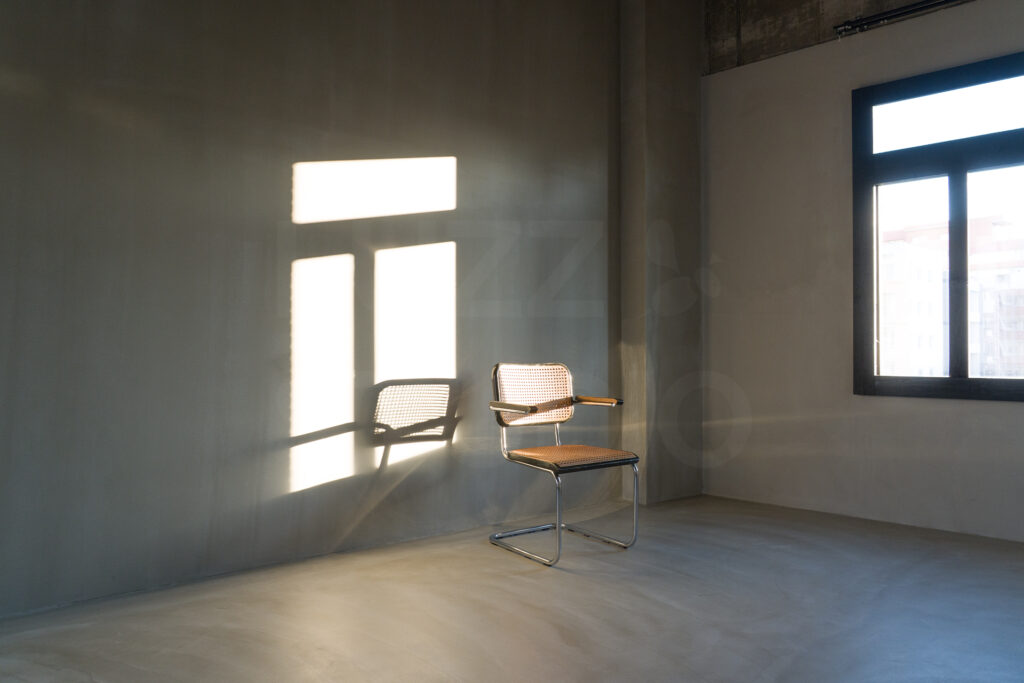コンクリート壁と床にラタンチェアを配置したスタジオ空間写真