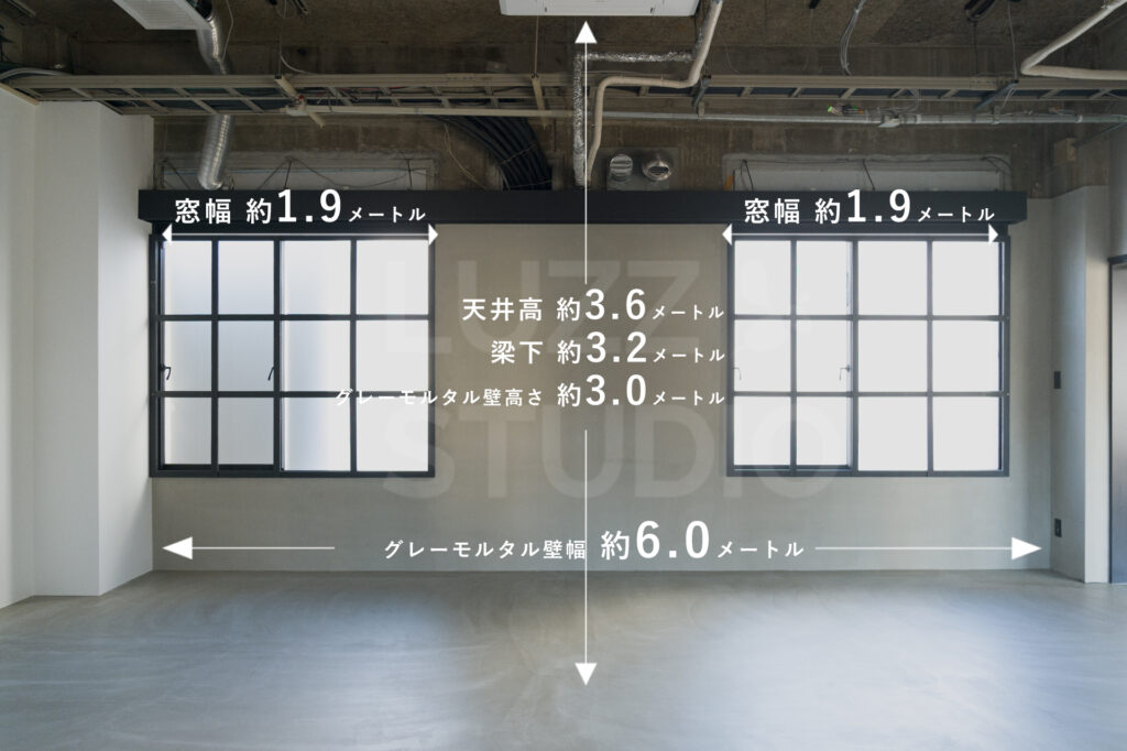 スタジオの窓側壁面のサイズ表記。天井高3.6メートル、梁下3.2メートル、グレーモルタル壁幅3.0メートル、格子状の窓幅1.9メートル。コンクリートの質感が広がる無機質なスタジオ内装