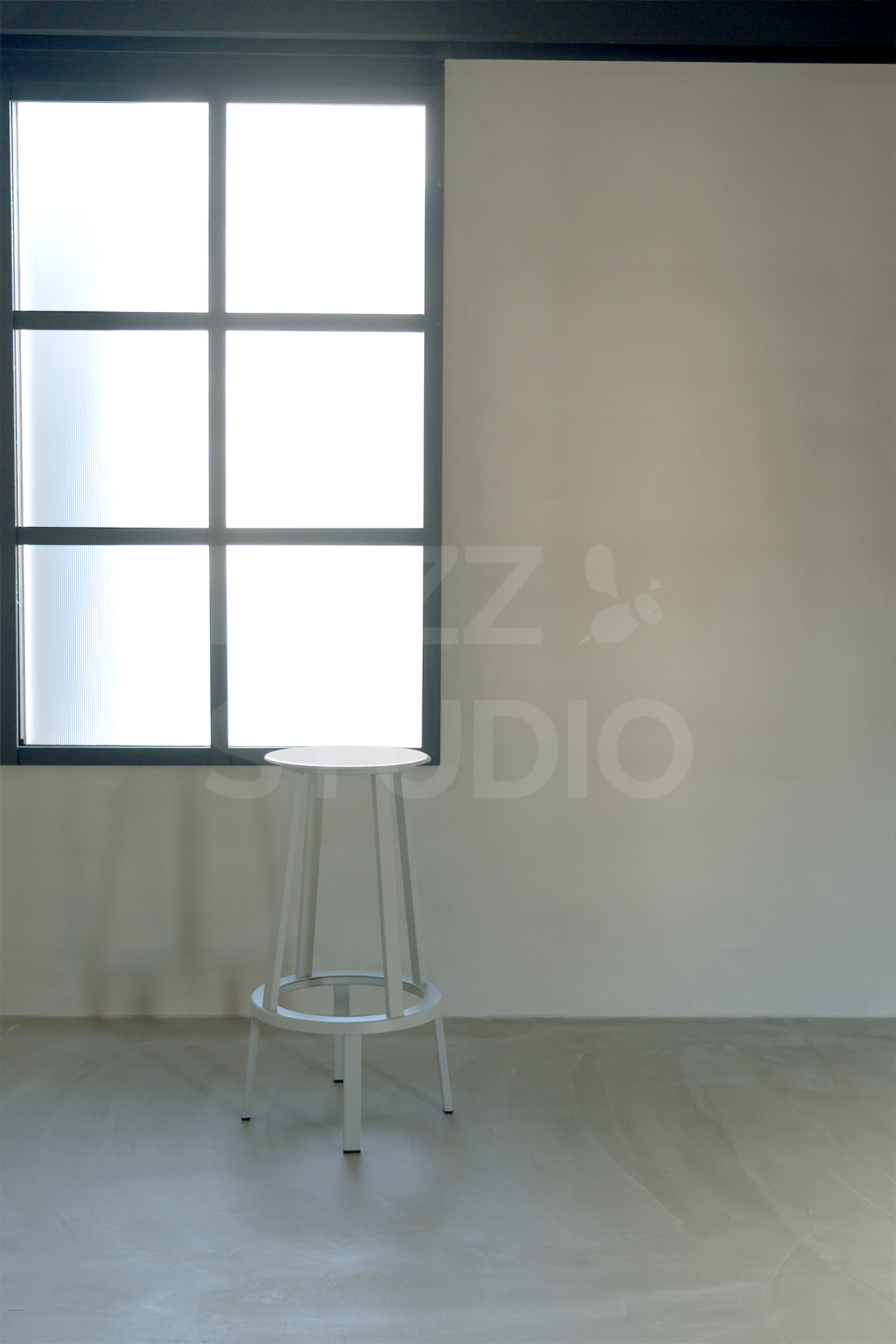 ラズスタジオのモルタルグレー床の部屋の黒窓枠を背景に、HAYのREVOLVER HI STOOLが置かれた室内写真