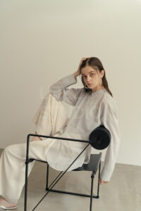 マリオ・ボッタ《Seconda Chair》に座るアパレルモデルの撮影事例。ポストモダンな椅子の幾何学的ラインと衣服のシルエットが共鳴し、モードで建築的な世界観を構築しているカット。