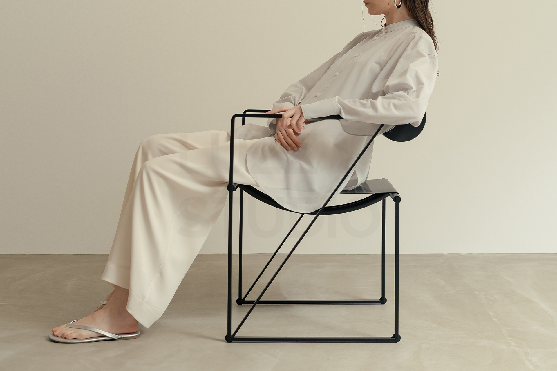 マリオ・ボッタ《Seconda Chair》に座るアパレルモデルの撮影事例。ポストモダンな椅子の幾何学的ラインと衣服のシルエットが共鳴し、モードで建築的な世界観を構築しているカット。