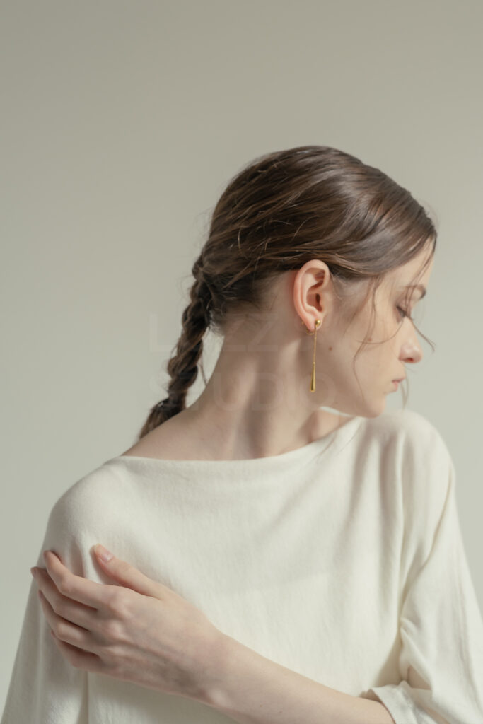 白壁の背景で座り込む商品のディティールをモデルの動きの中でとらえたＥＣアパレルのモデル撮影写真