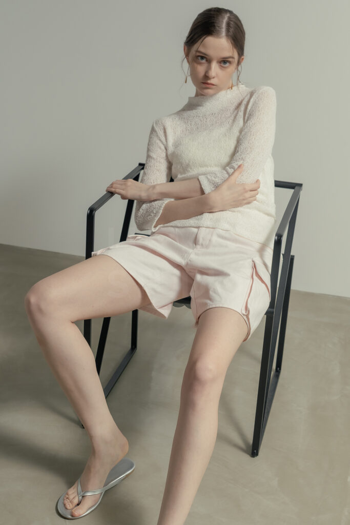 白壁モルタルグレー壁のシチュエーションで椅子に腰かけ自然な動きをとらえたECアパレルのモデル撮影写真