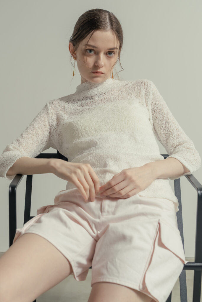 白壁モルタルグレー壁のシチュエーションで椅子に腰かけ自然な動きをとらえたECアパレルのモデル撮影写真