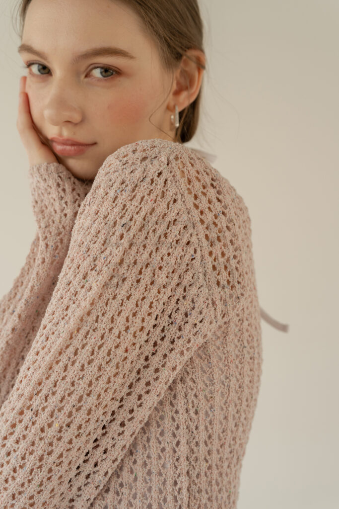 白壁背景でニット素材のディティールを訴求するように撮影されたレディスアパレルEC撮影写真