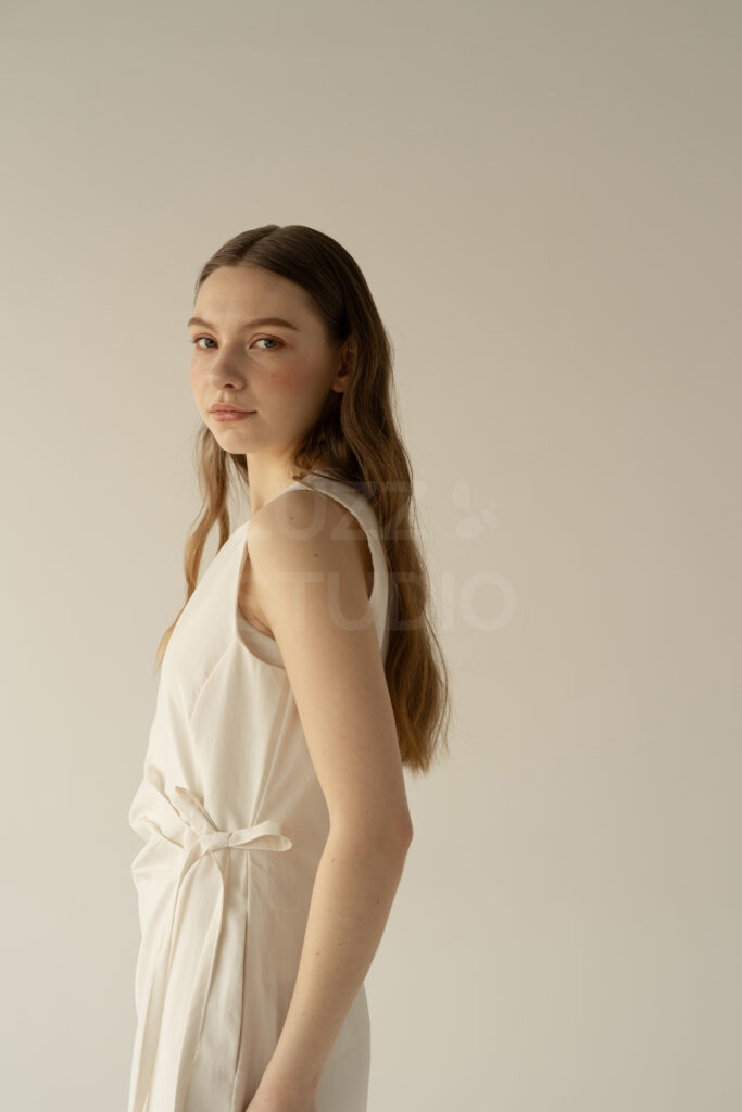 白壁白床の背景で振り向いているモデルを撮影したレディスアパレルEC撮影写真