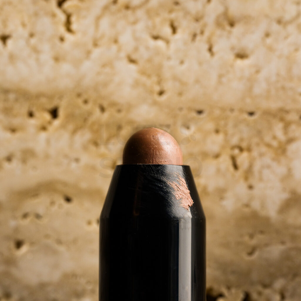 トラバーチンの凹凸と質感を背景に使用したメイクアップ化粧品の商品撮影画像