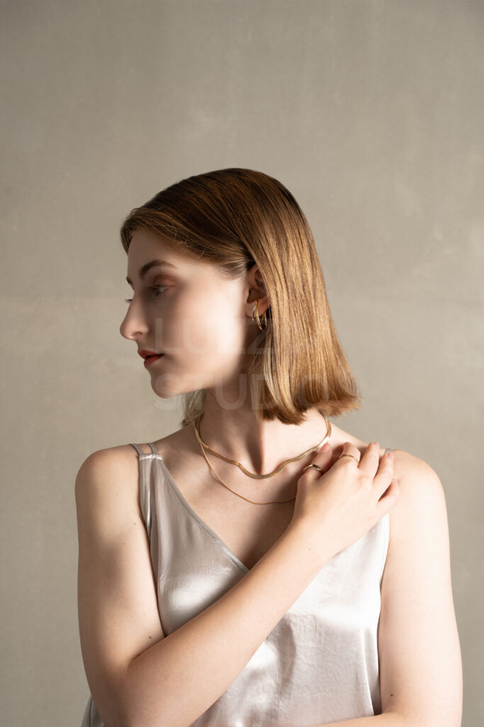 LUZZ STUDIOのモルタル壁を背景にしたモダンな雰囲気の女性モデルによるジュエリー撮影事例
